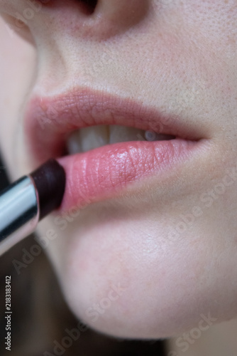 Applying tinted lip balm close up, woman putting on sheer pink lipstick, macro of female lips getting glossy tint moisturizer, daily makeup routine concept