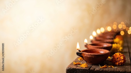 Diwali lamps, traditional diwali oil lamps lit on a wooden table, with marigold flowers, banner format with copy space