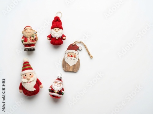 A Collection of Small Santa Claus Christmas Ornaments Arranged on a White Surface