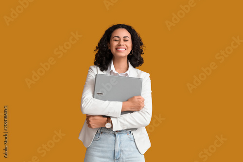 Happy female African-American job applicant with folder on orange background