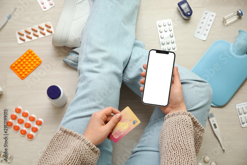 Woman with modern mobile phone, credit card, different medicines and medical ...