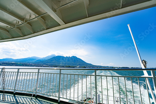Quadro su tela Mountain and coastline viewed from a moving ferry across a bright blue bay