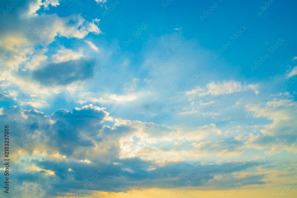 Fototapeta premium A bright sky at sunrise. A background of clouds in the blue sky with an orange section below.