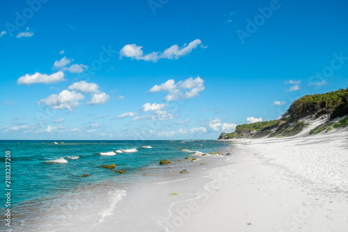 A seaside coastline with dunes and white sand. A panorama of an empty beach in summer.