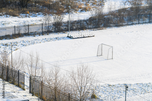 A small soccer field covered in snow with empty goals. A playground for children's competitions, closed for the winter.