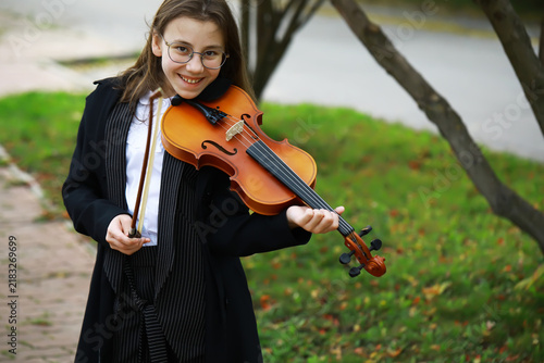 Quadro su tela Young Girl Smiling While Playing Violin Outdoors on a Sunny Day