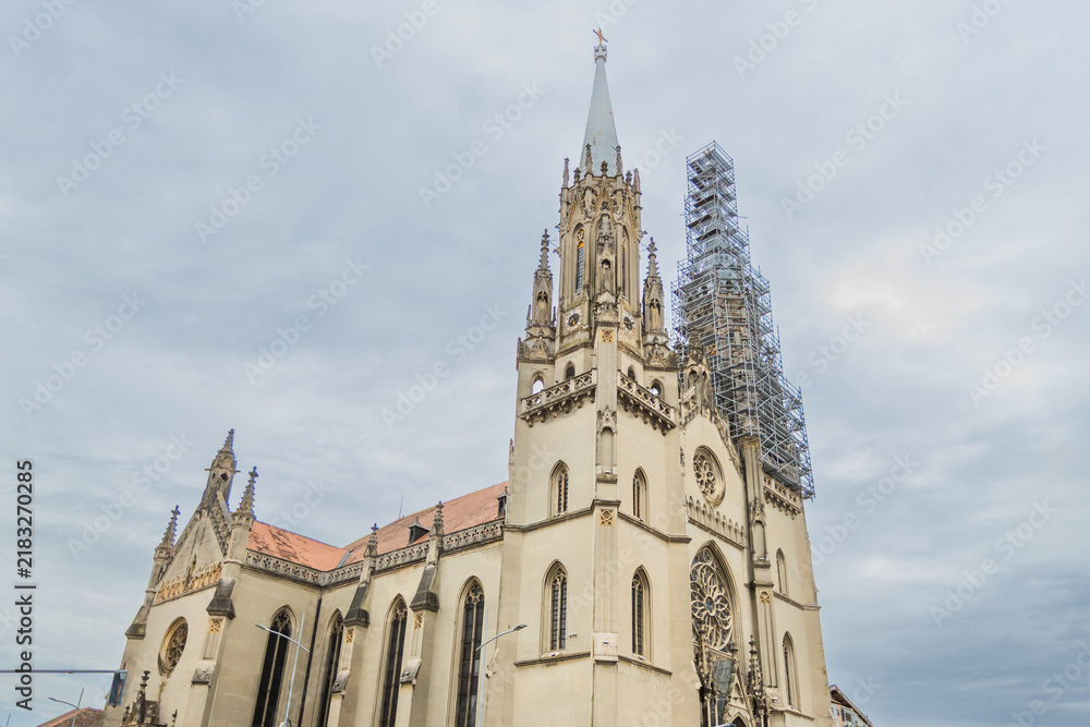 Fototapeta premium Gothic spire pierces the sky beside restoration scaffolding