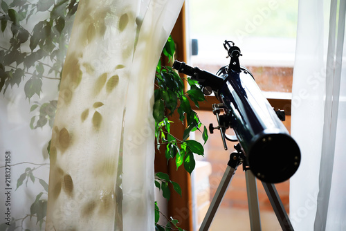 Принти на полотні Home Astronomy Setup: Telescope by Sunlit Window with Green Foliage