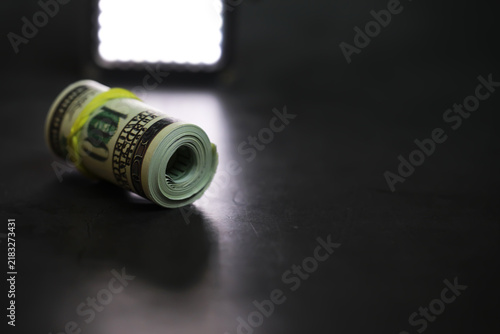 Bild auf Leinwand Rolled Up Cash on Dark Surface Under Bright Light: Financial Security Concept