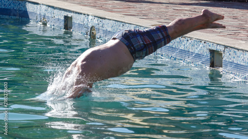 Man dives headfirst into clear blue swimming pool