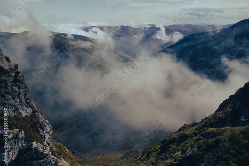 Foto Thick white fog rising from a steep dangerous mountain drop