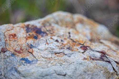 Fotografía Macro view of weathered sandstone with rusty orange and dark mineral staining, cracked surface and flaking rock layers, revealing natural geological erosion and oxidation