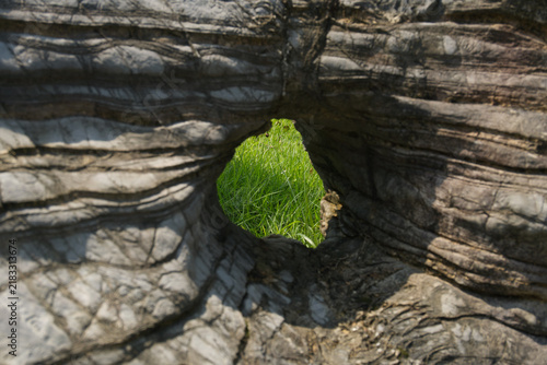 Foto natural rock formation with hole overlooking green grass field
