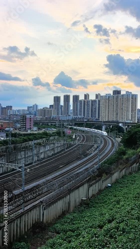 Vertical Video: High-speed train weaving through layers of city buildings under a warm sunset
