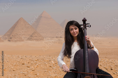 Obraz na płótnie Serene Middle Eastern female cellist seated with cello before the iconic Giza py