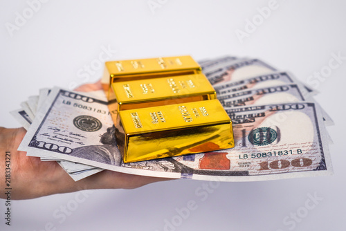 Canvastavla A person's hand holding a stack of US$100 bills and three gold bars