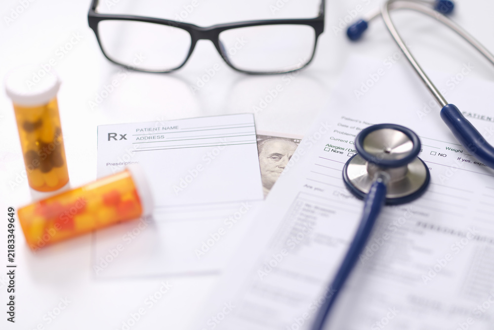 Obraz premium Bright medical workspace with prescription forms, stethoscope, eyeglasses, pill bottles and partial cash note on white desk, illustrating healthcare, medication review, patient paperwork and bribery