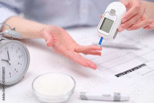 Фотография Close view of hands using glucometer for fingertip blood sugar check beside alar