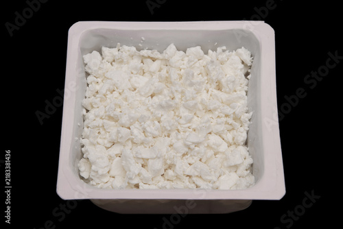Cottage cheese in container isolated on black background. Side view. Smooth and creamy curd