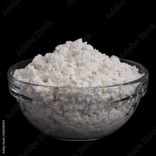 Cottage cheese in glass bowl isolated on black background. Side view of Delicious milk product