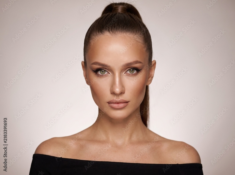 Fototapeta premium Studio portrait of beautiful woman with bare shoulders winged eyeliner and sleek high ponytail
