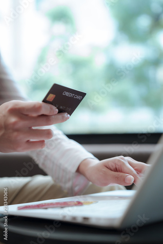 Close-up of an Asian woman using a smartphone and credit card for digital payment, highlighting cashless transactions, fintech technology, online shopping, and modern finance.