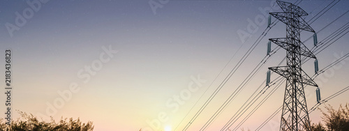 High-voltage electricity transmission pylon against a twilight sky transitioning to a starry night, symbolizing power infrastructure and energy distribution. Concept of the electricity energy industry