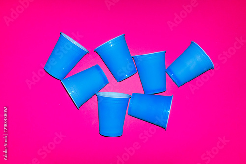 Several blue plastic cups cover a bright pink background