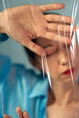 A woman presses her hand against a suffocating plastic film