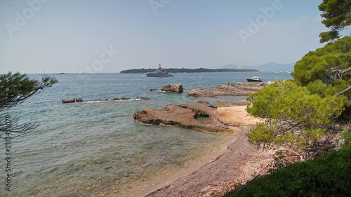 Luxury yacht sailing in clear blue Mediterranean waters near rocky coastline