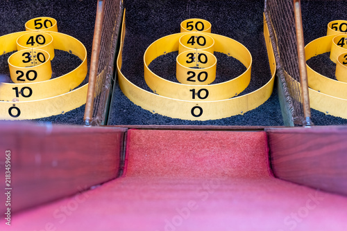 Skee ball game setup with numbered rings at an amusement arcade