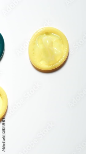 TOP VIEW: Male hand takes a colour condom from a white table - Close Up