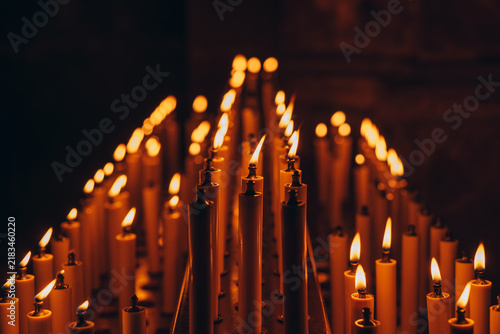 Candles burning in a dark space creating warm light and highlighting their shapes