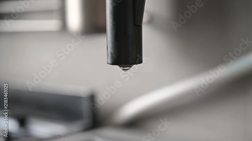Close-up of water dripping from a faucet, showing liquid formation and flow