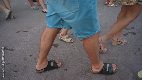 People walking in summer sandals on a paved surface with scattered cigarette butts