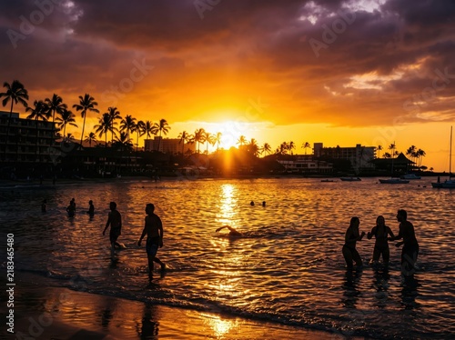 Golden tropical sunset beach scene with silhouettes of people swimming, warm orange sunset over ocean bay with palm trees