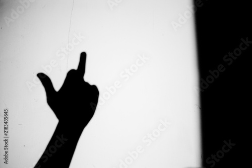 Фотография Close up black and white shadow of hand showing middle finger gesture on the dir