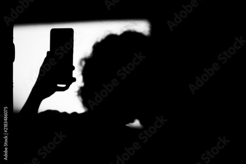 Close up black and white portrait shadow of man holding smartphone on the dirty wall