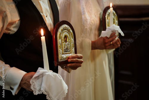 Foto Bride and groom holding traditional religious wedding candles and sacred icons d
