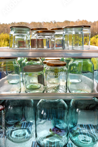 Empty glass jars with metal lids on the shelves near the window.