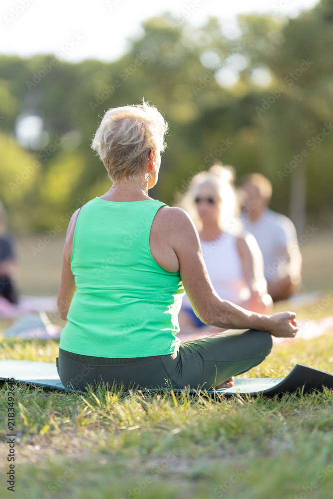 Obraz premium Senior woman meditating in outdoor yoga class