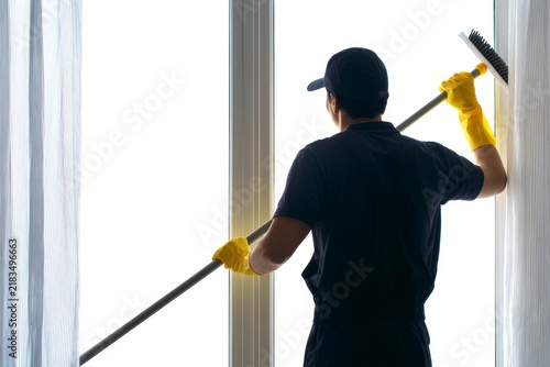 Professional window cleaner performing his task with precision and care while wearing yellow rubber gloves in a bright indoor environment. Generative AI
