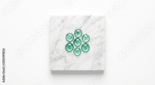 Top-down view of botanical essence droplets on honed white Carrara marble slab