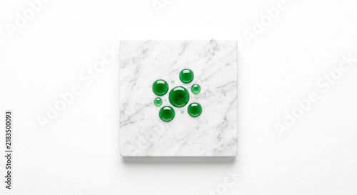 Top-down view of botanical essence droplets on honed white Carrara marble slab