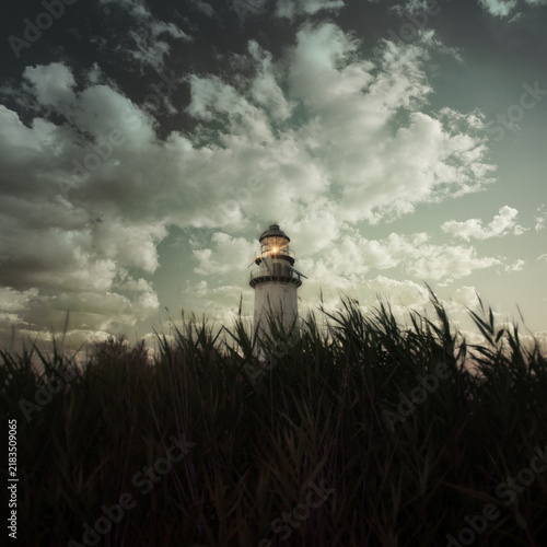 Moody Lighthouse Emerging From Reeds Under Stormy Sky