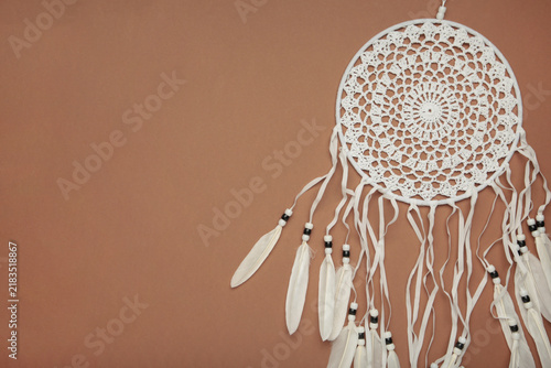 Cuadro en lienzo Handmade dream catcher hanging on a rope with feathers, threads, and beads on brown background