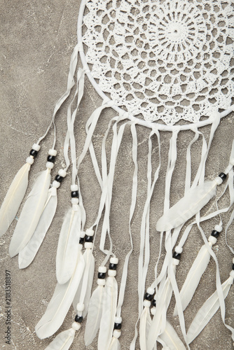 Fotografía Handmade dream catcher hanging on a rope with feathers, threads, and beads on grey concrete background