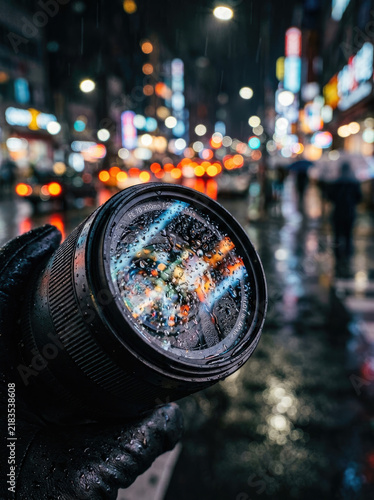 Rain drops on camera lens create vibrant urban scene at night, showcasing reflections and lights