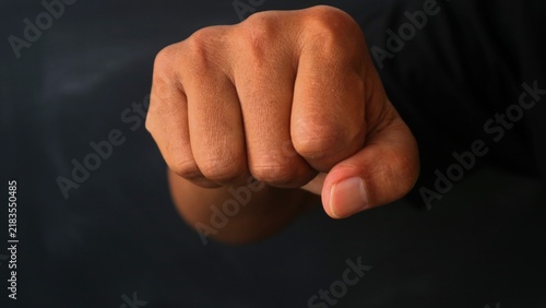 Картината върху платно A close up view of a human hand clenched into a tight fist against a dark background