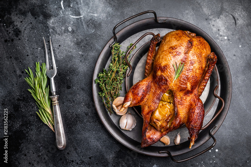 Fotografie Roasted whole goose on steel tray. black background. top view